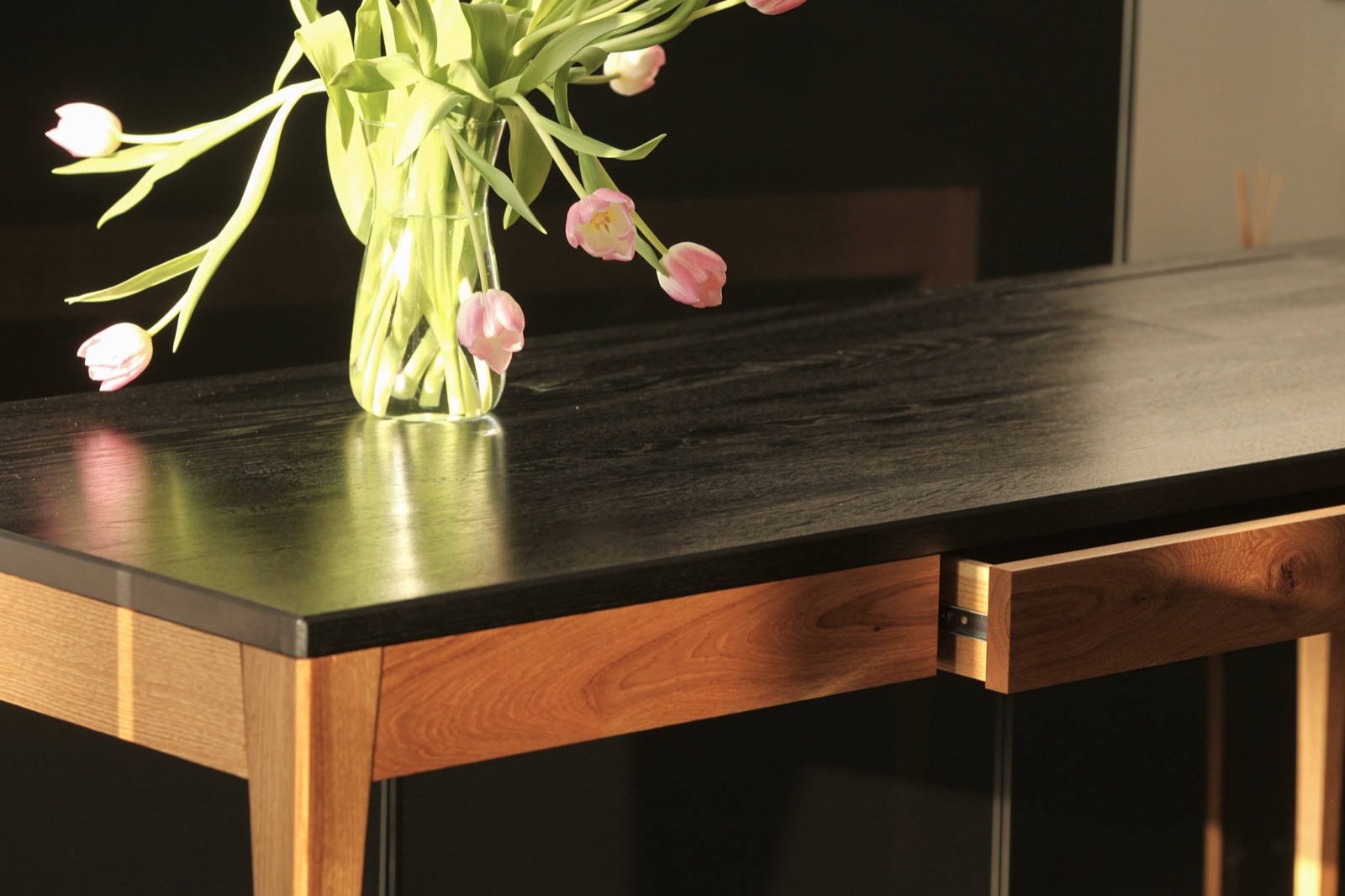 Adriana One-Piece with a dark top, a vase of tulips and the drawer open