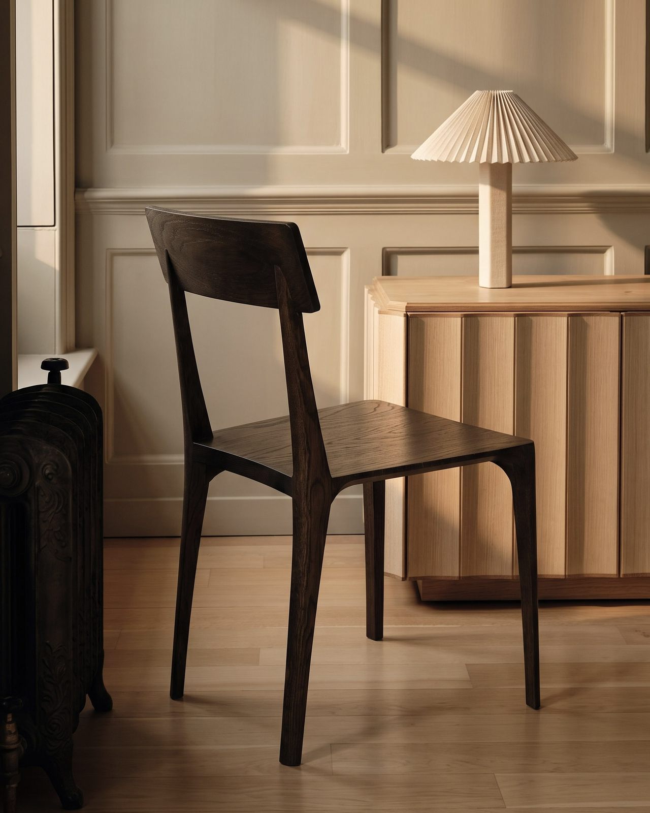 A dark Pilar chair at a small table in a panelled room